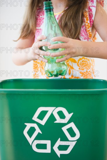 Close up of girl (6-7) throwing plastic bottle to recycling bin. Photo : Jamie Grill