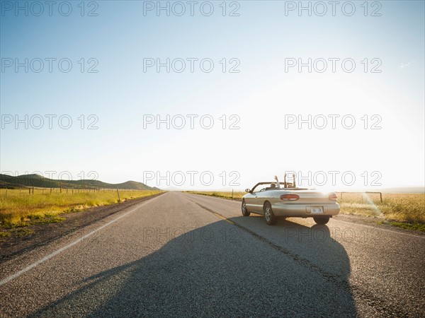 Happy couple driving on empty road. Photo: Erik Isakson