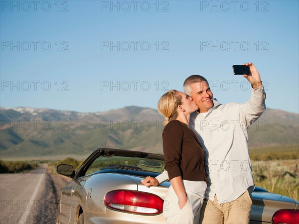 USA, Utah, Kanosh, Mid adult couple photographing themselves in front of majestic mountain range. Photo: Erik Isakson