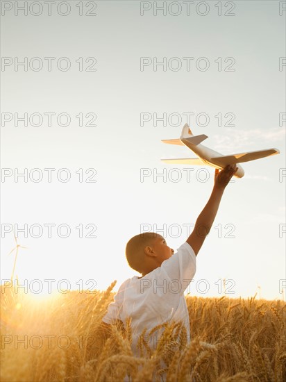 Boy (10-11) playing with toy aeroplane in wheat field. Photo: Erik Isakson