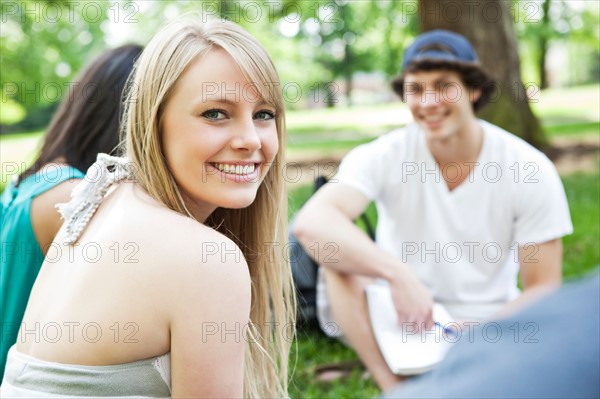 Portrait of young woman with friends in park. Photo: Take A Pix Media