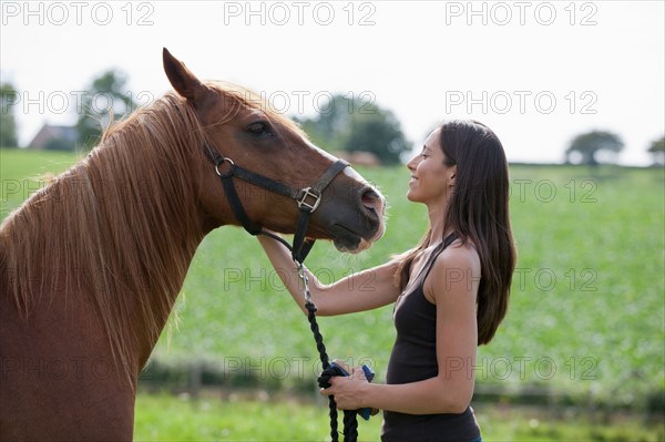 Young woman with horse in field. Photo : Jan Scherders