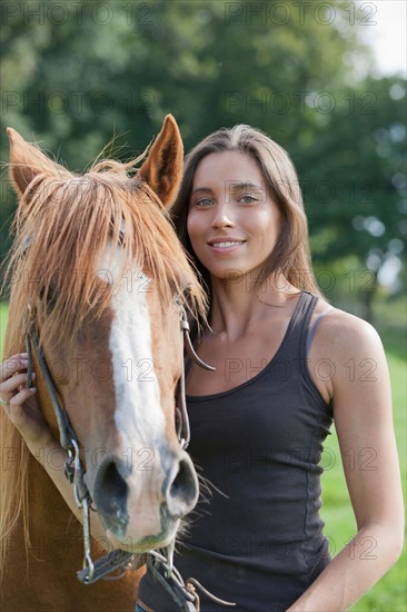 Portrait of young woman with horse in field. Photo : Jan Scherders