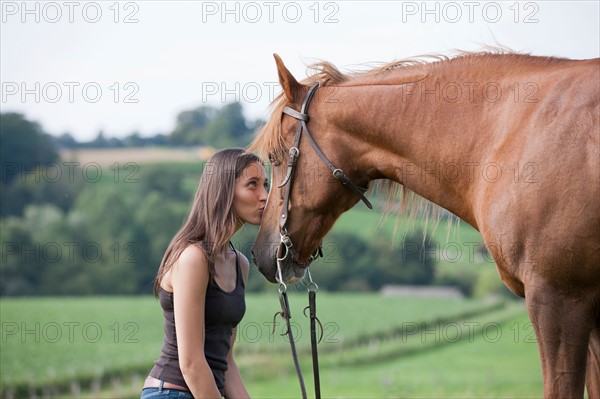 Young woman kissing horse in field. Photo : Jan Scherders