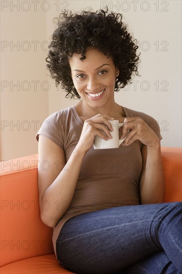 Portrait of young woman sitting on sofa. Photo: Rob Lewine