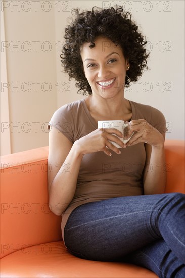 Portrait of young woman sitting on sofa. Photo : Rob Lewine