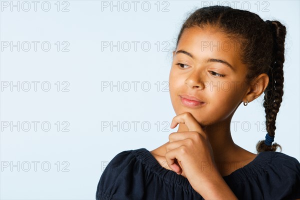 Studio portrait of girl (10-11) with hand on chin. Photo : Rob Lewine