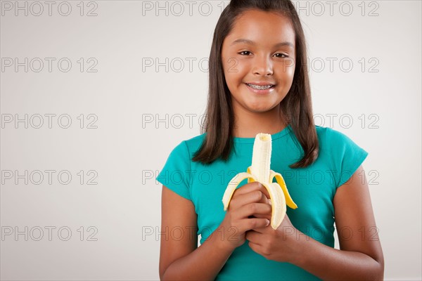 Studio portrait of girl (10-11) holding banana. Photo : Rob Lewine