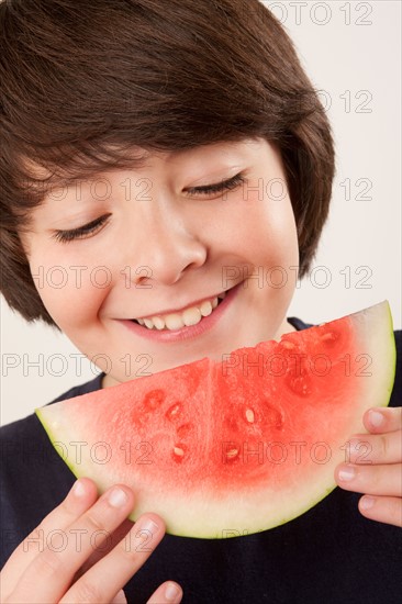 Studio portrait of boy (10-11) eating watermelon. Photo: Rob Lewine