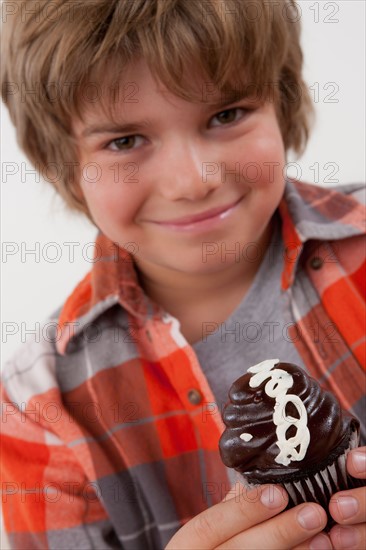 Studio portrait of boy (8-9) holding cake. Photo: Rob Lewine