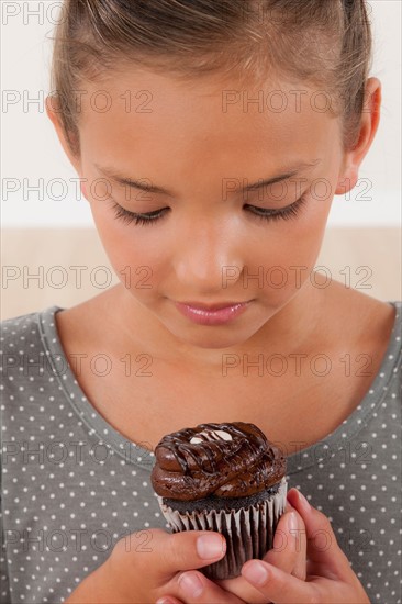 Studio portrait of girl (8-9) holding cake. Photo : Rob Lewine