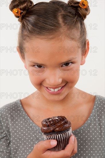 Studio portrait of girl (8-9) holding cake. Photo : Rob Lewine