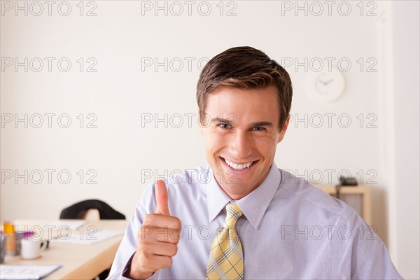 Portrait of businessman with thumbs up. Photo : Rob Lewine