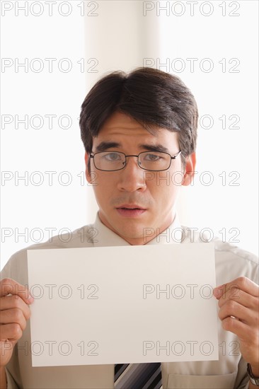 Studio shot of business man holding blank paper. Photo : Rob Lewine