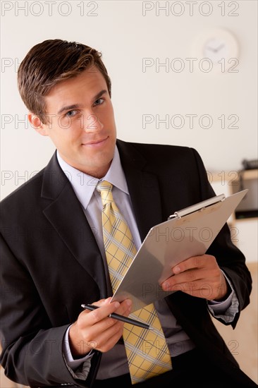 Portrait of businessman holding clipboard. Photo: Rob Lewine