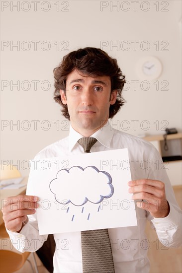 Studio portrait of businessman holding sheet of paper with cloud drawing. Photo : Rob Lewine