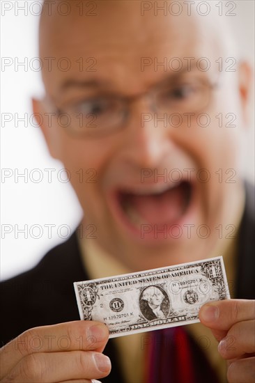 Portrait of business man holding one dollar bill. Photo : Rob Lewine