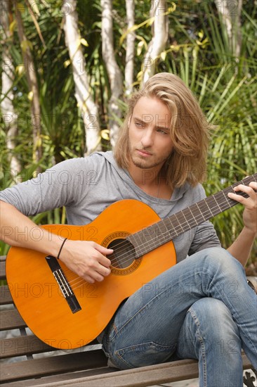 Young man playing guitar in park. Photo : Rob Lewine