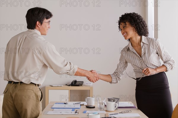 Businessman and businesswoman handshake during meeting. Photo: Rob Lewine