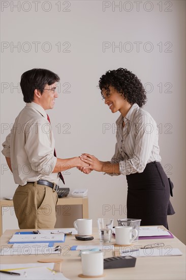 Businessman and businesswoman handshake during meeting. Photo : Rob Lewine