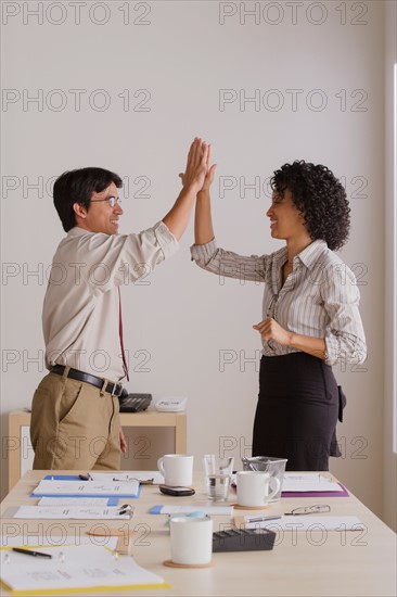 Businessman and businesswoman high fiving. Photo : Rob Lewine