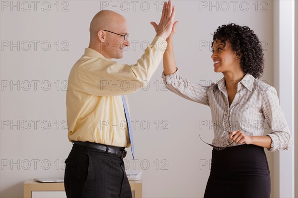 Businessman and businesswoman high fiving. Photo: Rob Lewine