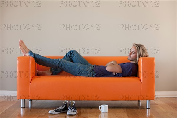 Young man lying on sofa. Photo: Rob Lewine