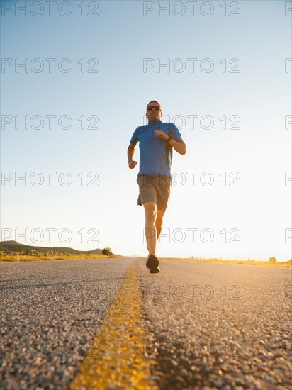 Mid adult couple running on empty road.