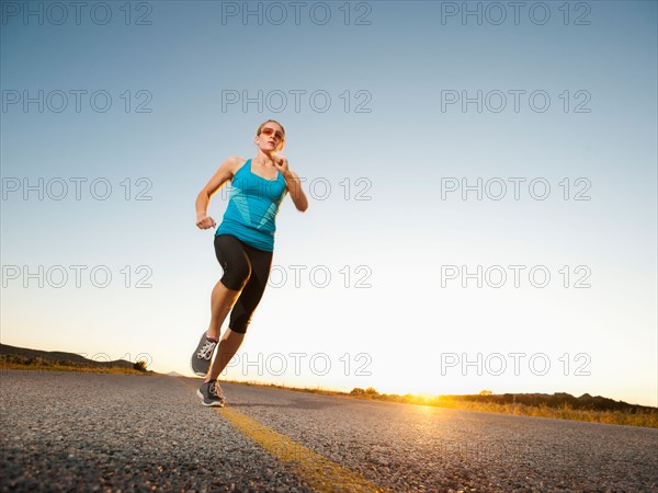 Mid adult couple running on empty road. Photo: Erik Isakson