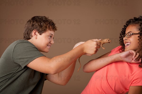 Studio shot of boy (12-13) teasing girl (10-11). Photo : Rob Lewine