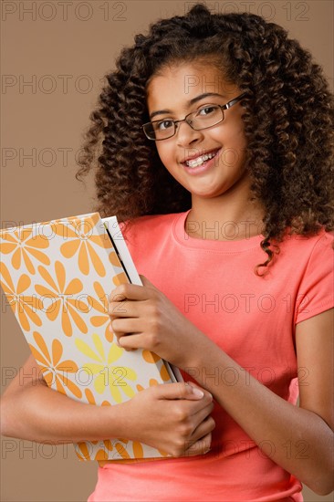 Studio portrait of girl (10-11) holding book. Photo : Rob Lewine