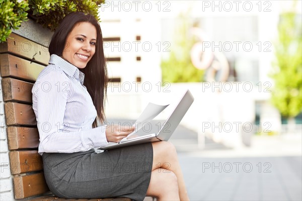 Portrait of young businesswoman sitting on bench using laptop. Photo : Take A Pix Media