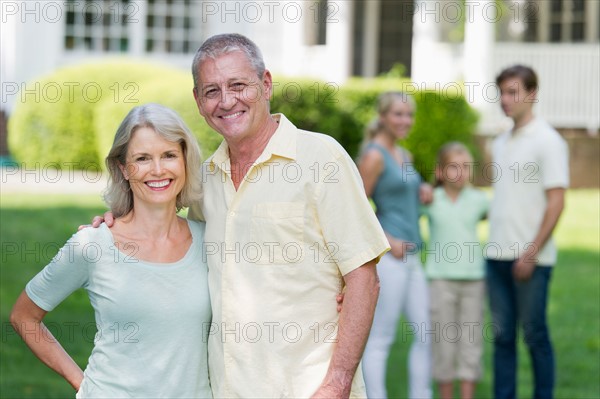 Portrait of senior couple, family in background.