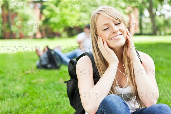 Woman listening to mp3 player in park. Photo: Take A Pix Media