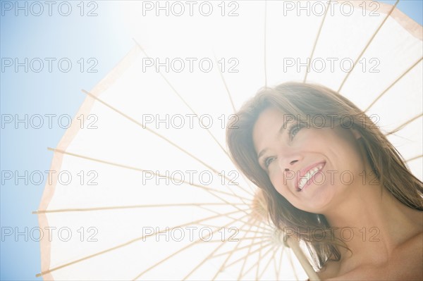 Woman in sunlight with parasol. Photo : Jamie Grill