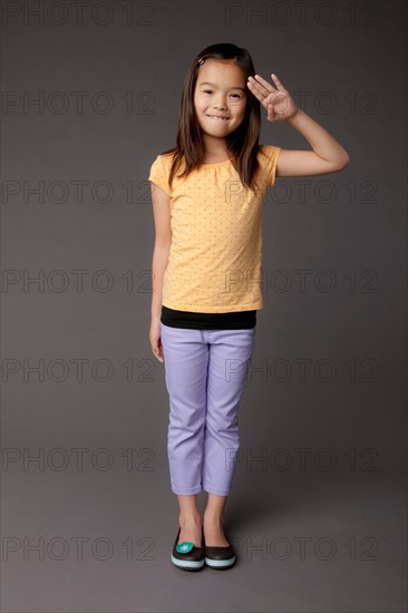 Studio portrait of girl (8-9) saluting. Photo : Rob Lewine