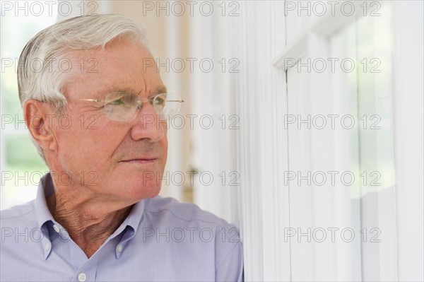 Portrait of senior man looking through window.