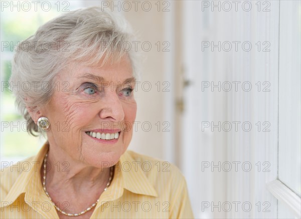 Portrait of senior woman looking through window.