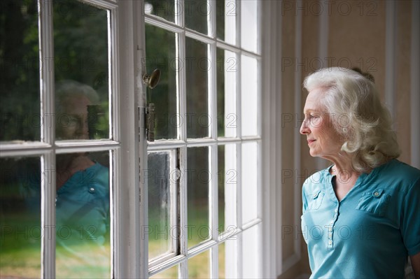 Senior woman looking through window.