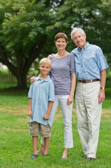 Three generation family standing in park.