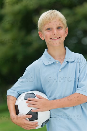 Boy (10-11) holding soccer ball.