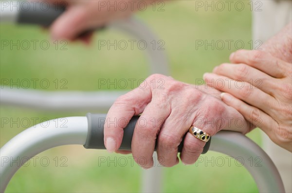 Senior walking with walker, close-up of hands.