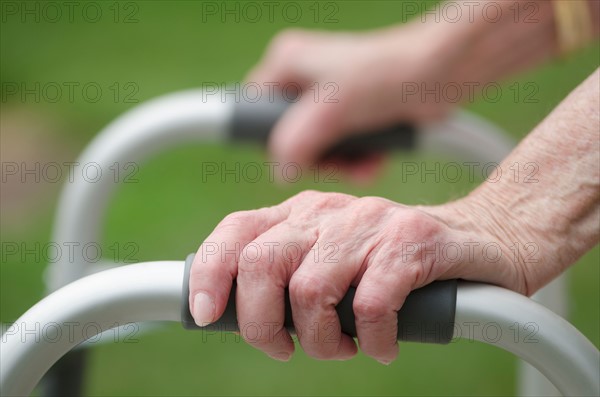 Senior walking with walker, close-up of hands.