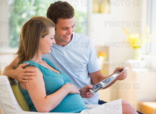 Happy parents watching ultrasound picture of baby.