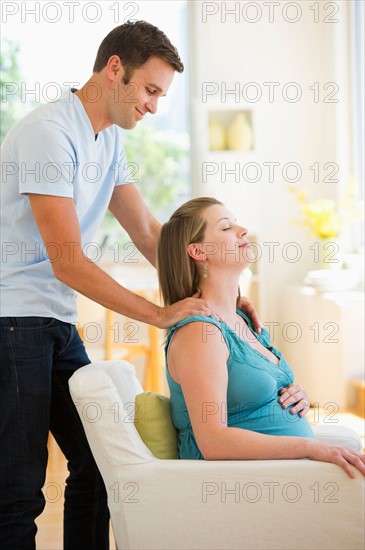 Young man massaging pregnant partner.