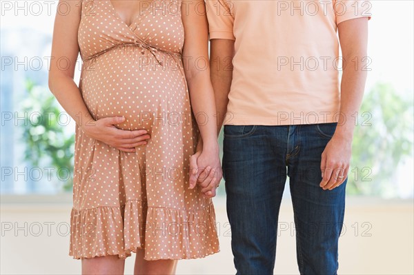 Pregnant woman holding partner's hand.