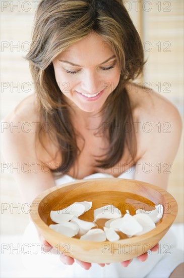 Woman in spa holding bowl with flower petals. Photo : Jamie Grill