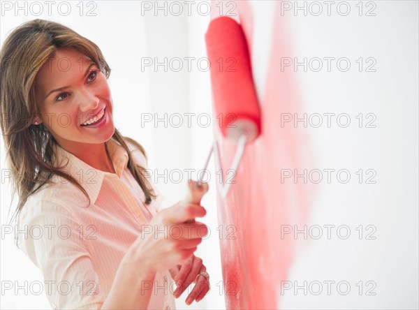 Woman painting wall with rollerpaint. Photo : Jamie Grill