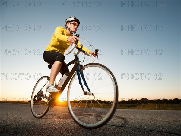 Mid adult woman cycling on empty road. Photo: Erik Isakson