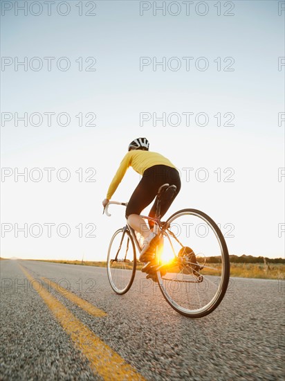 Mid adult woman cycling on empty road. Photo: Erik Isakson